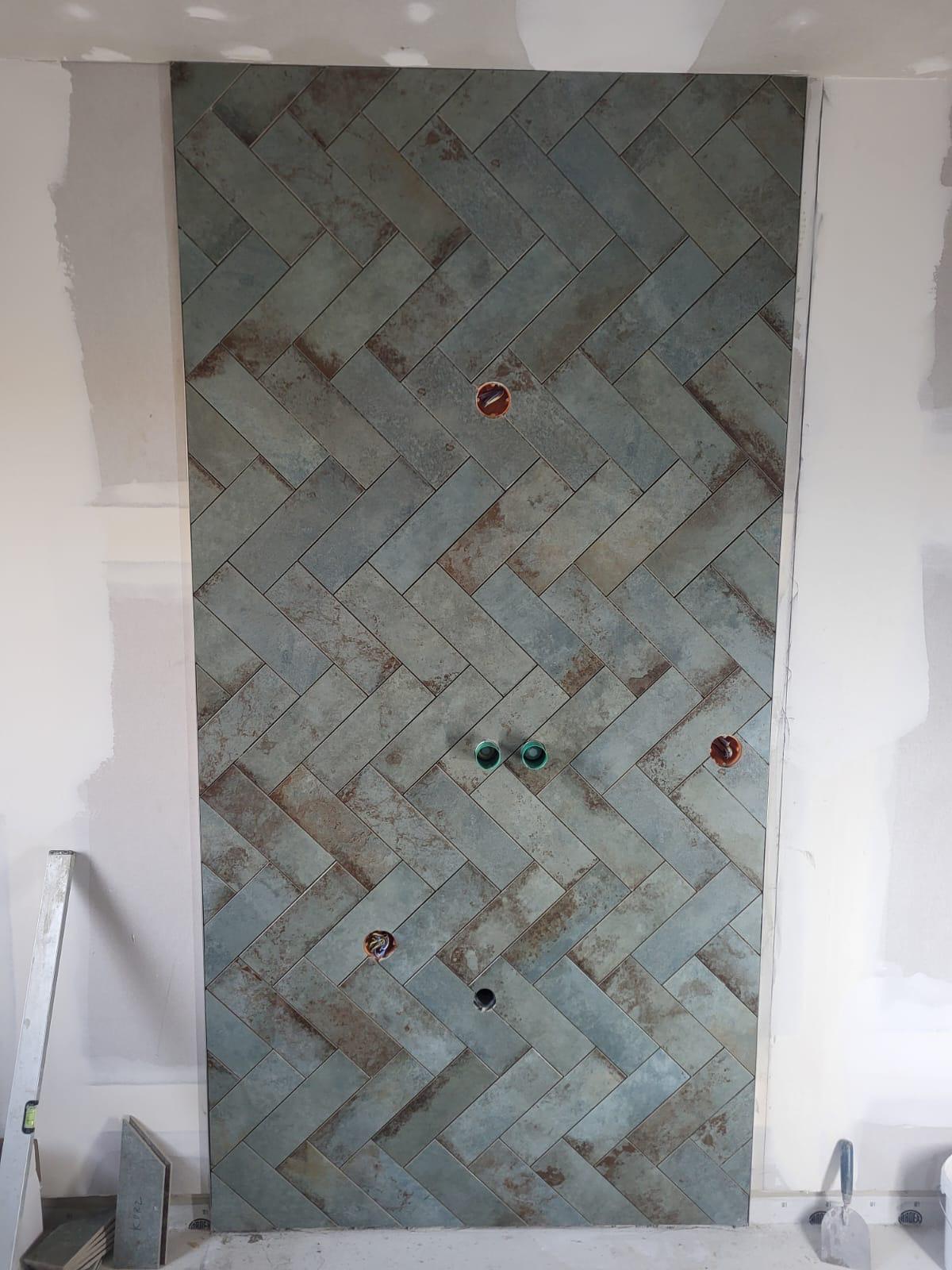 Fliesen in Fischgrätenmuster. Ziegelwand mit Fischgrätenmuster, versehen mit bunten Steinen.