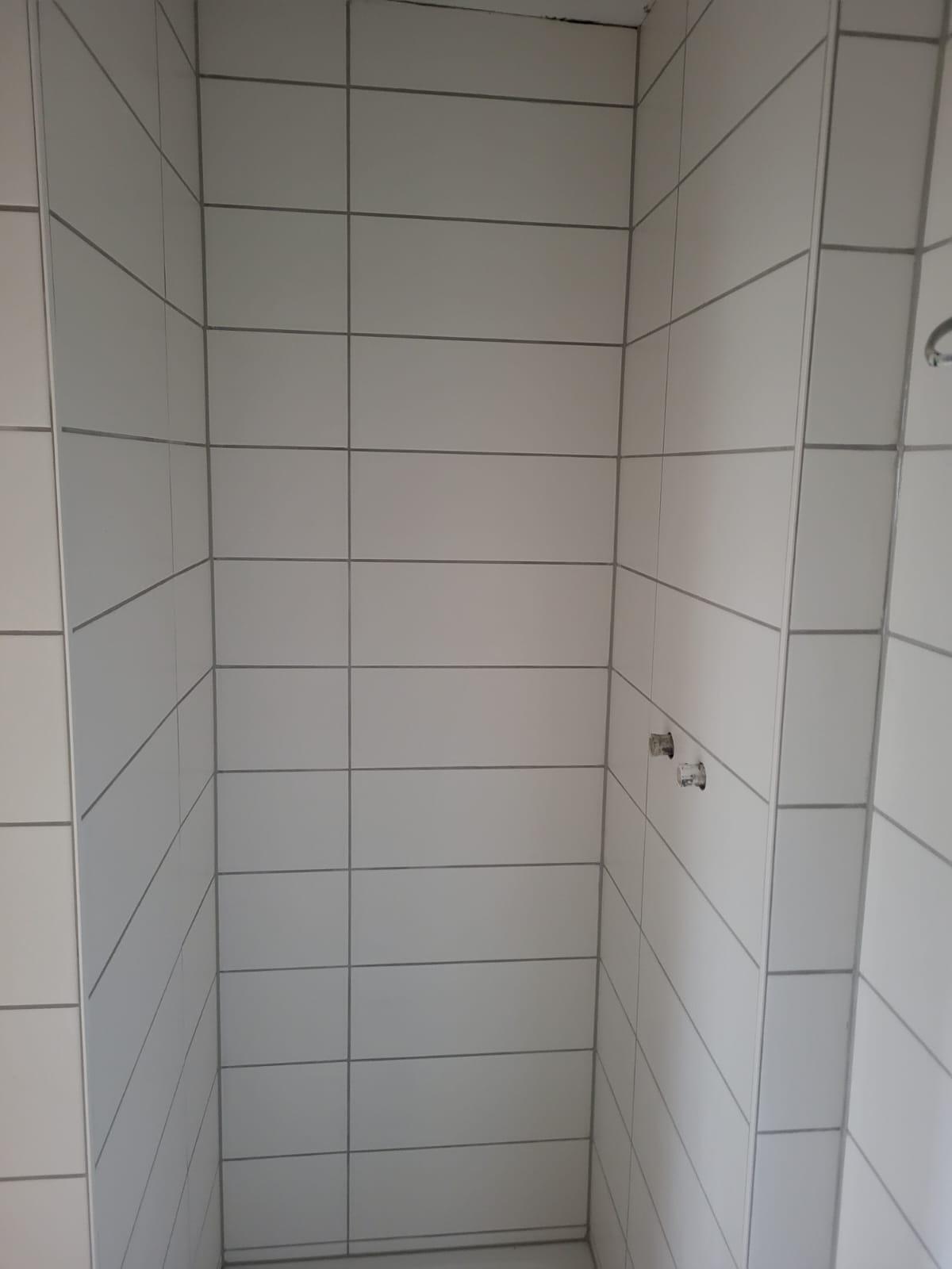 Dusche Weiße geflieste Duschwand mit vertikalen und horizontalen Fugen.