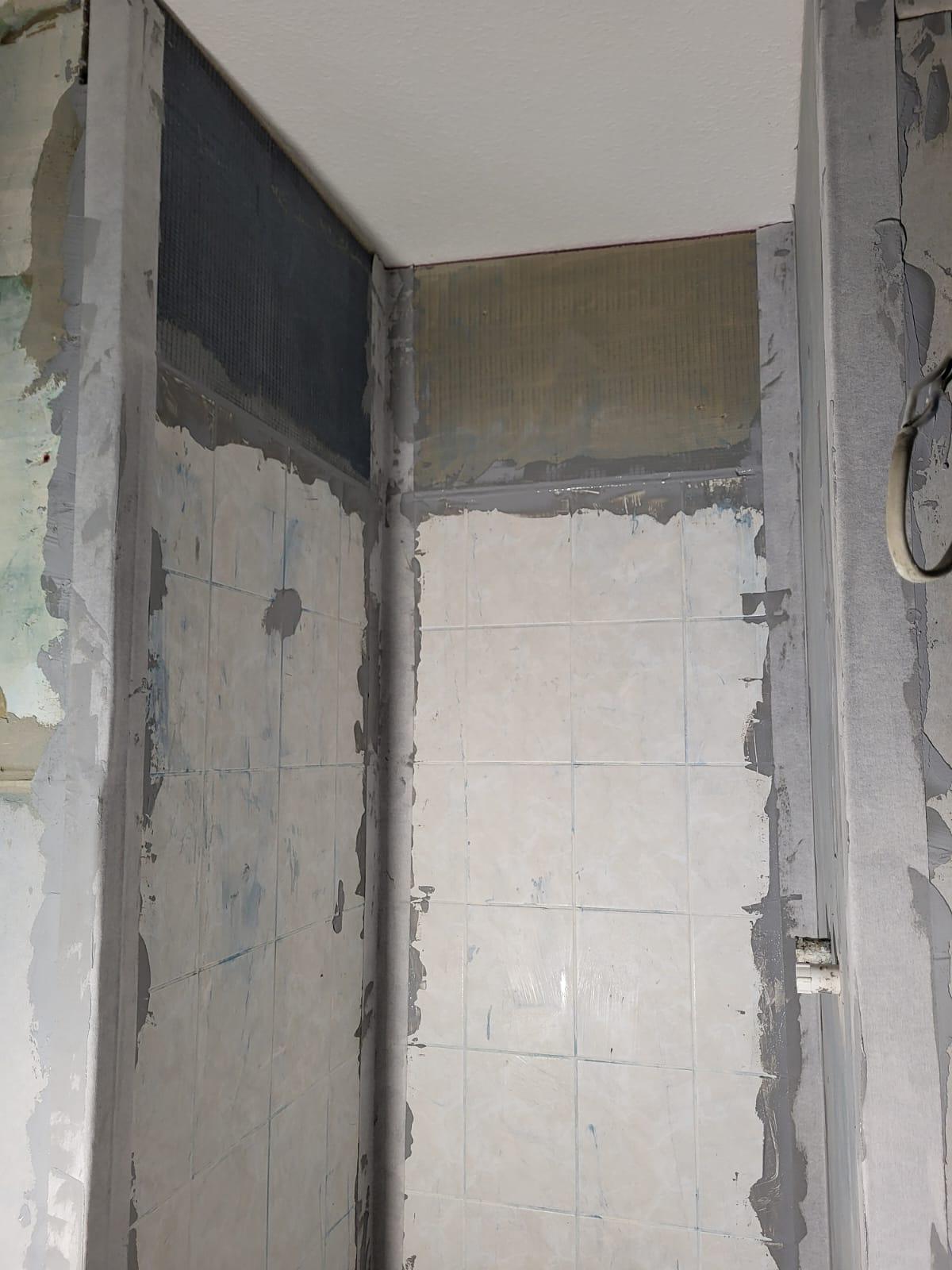 Vorbereitete Neubaudusche Unfertig renovierter Duschbereich mit unebenem Putz und freiliegenden Wänden.