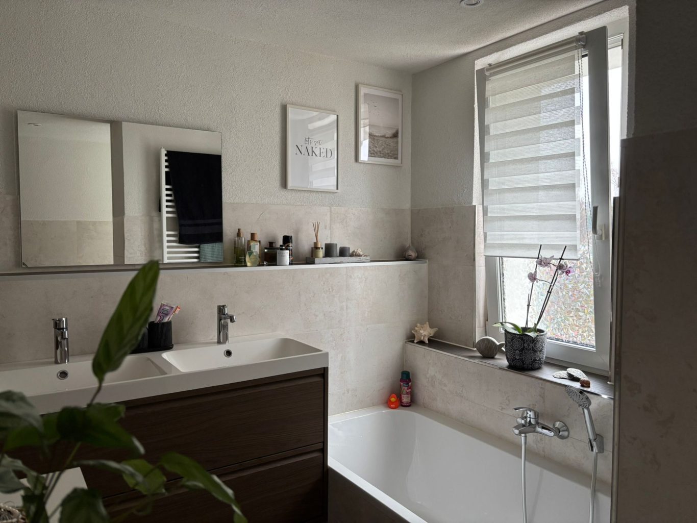 Neubaubad Modernes Badezimmer mit Badewanne, Doppelwaschbecken und Fenster mit Jalousien.