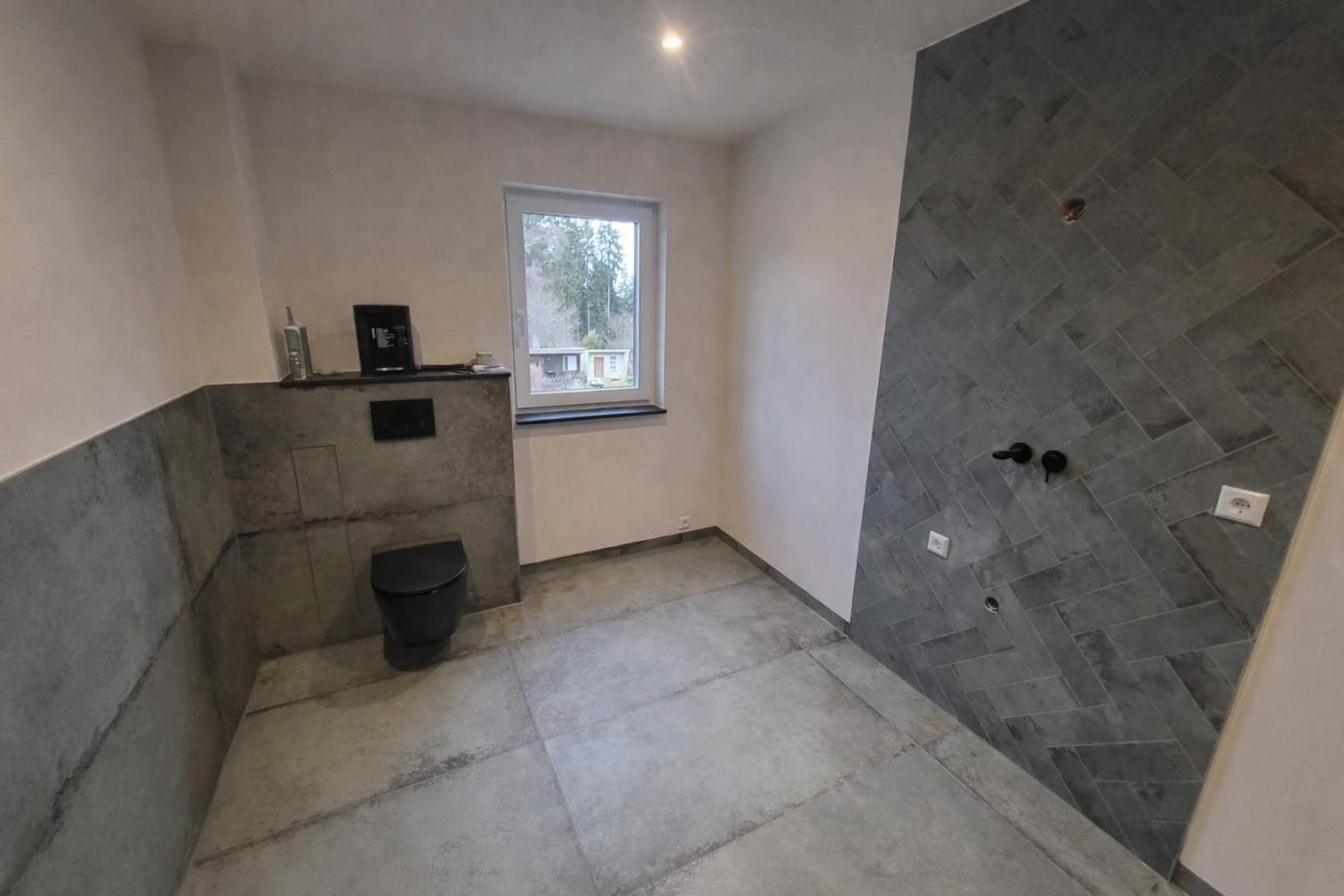 Fertiges Badezimmer Helle, leere Raum mit grauen Wänden und Betonboden, Fensterplatz sichtbar.