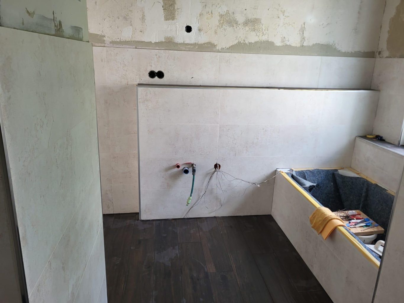 Vorwandelement für Waschbecken Küchenbereich mit unvollständigen Wänden und Wasseranschlüssen. Holzboden sichtbar.